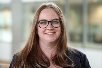Medium shot of Melissa Mills wearing glasses and smiling to the camera.